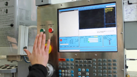 an up-close image of a CNC Milling Machine used by Centrx inc., A Pittsburgh contract manufacturer, The image is showing a control panel with lots of buttons and a LCD screen, there is also a mans hand pushing an on button.